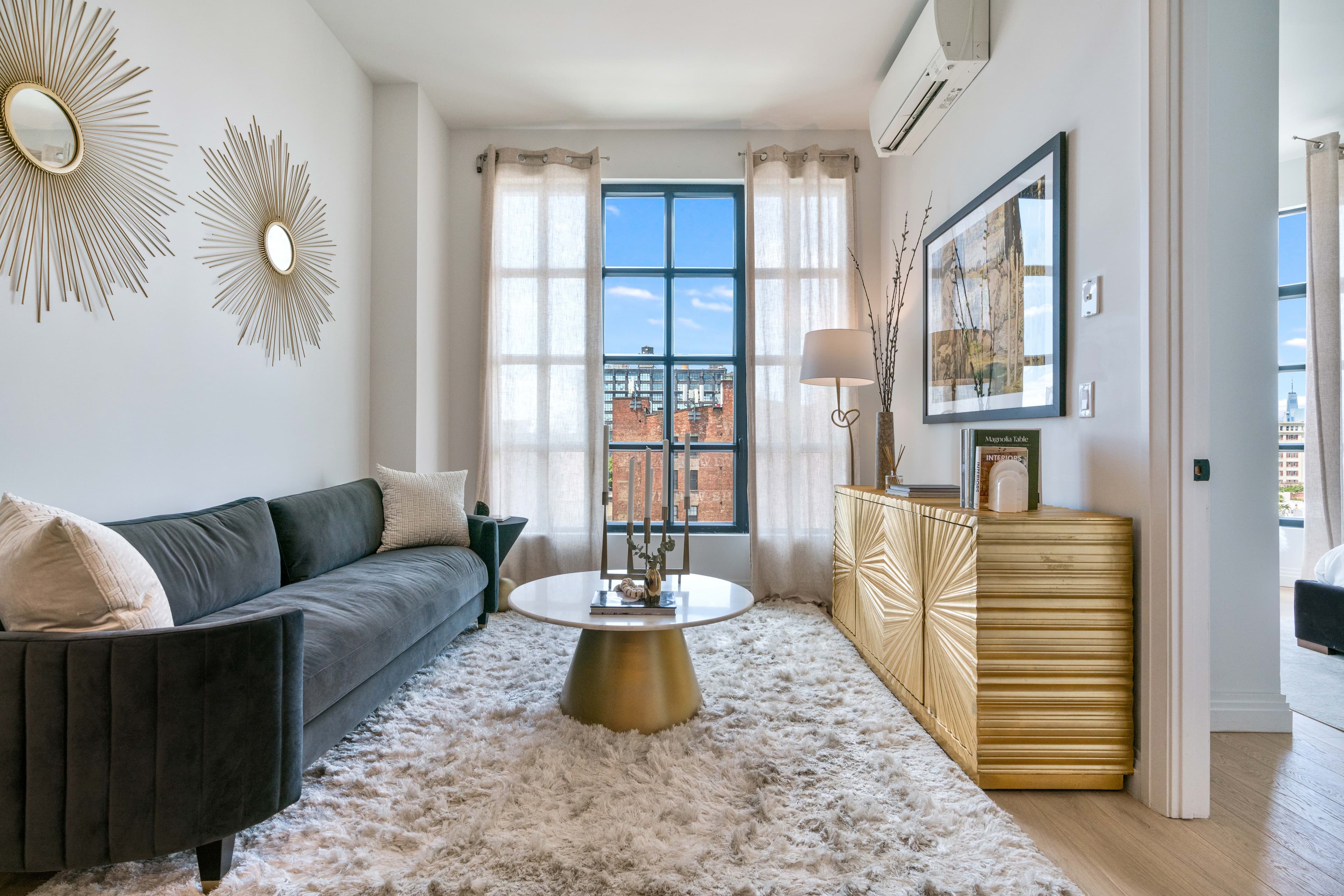 The living area of a one bedroom residence at 875 Fourth Avenue with an oversized window and wide-plank floors