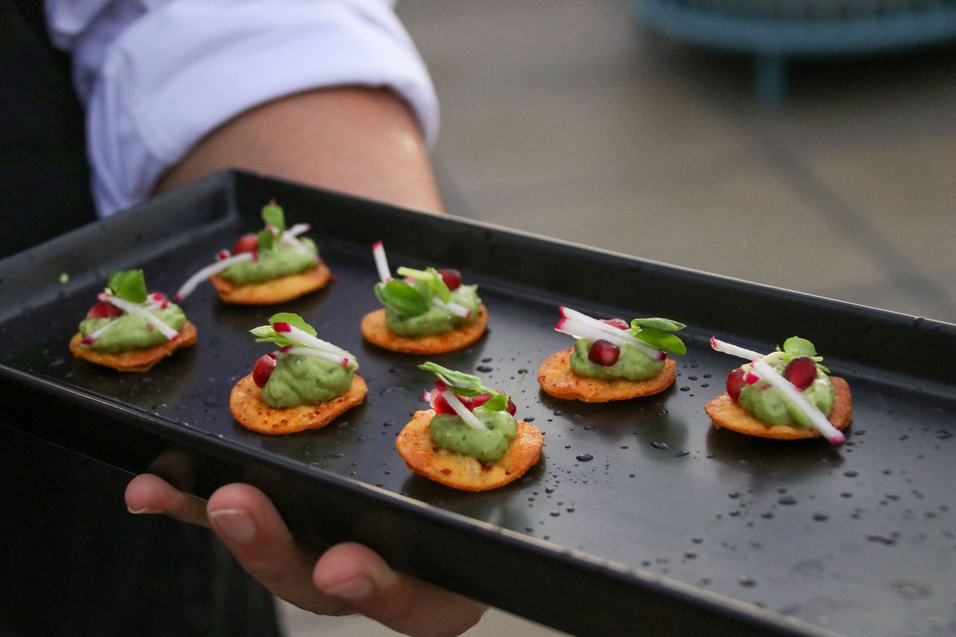 A tray of canapes topped with herbs, radish and pomegranate, served on the rooftop terrace at 875 Fourth Avenue