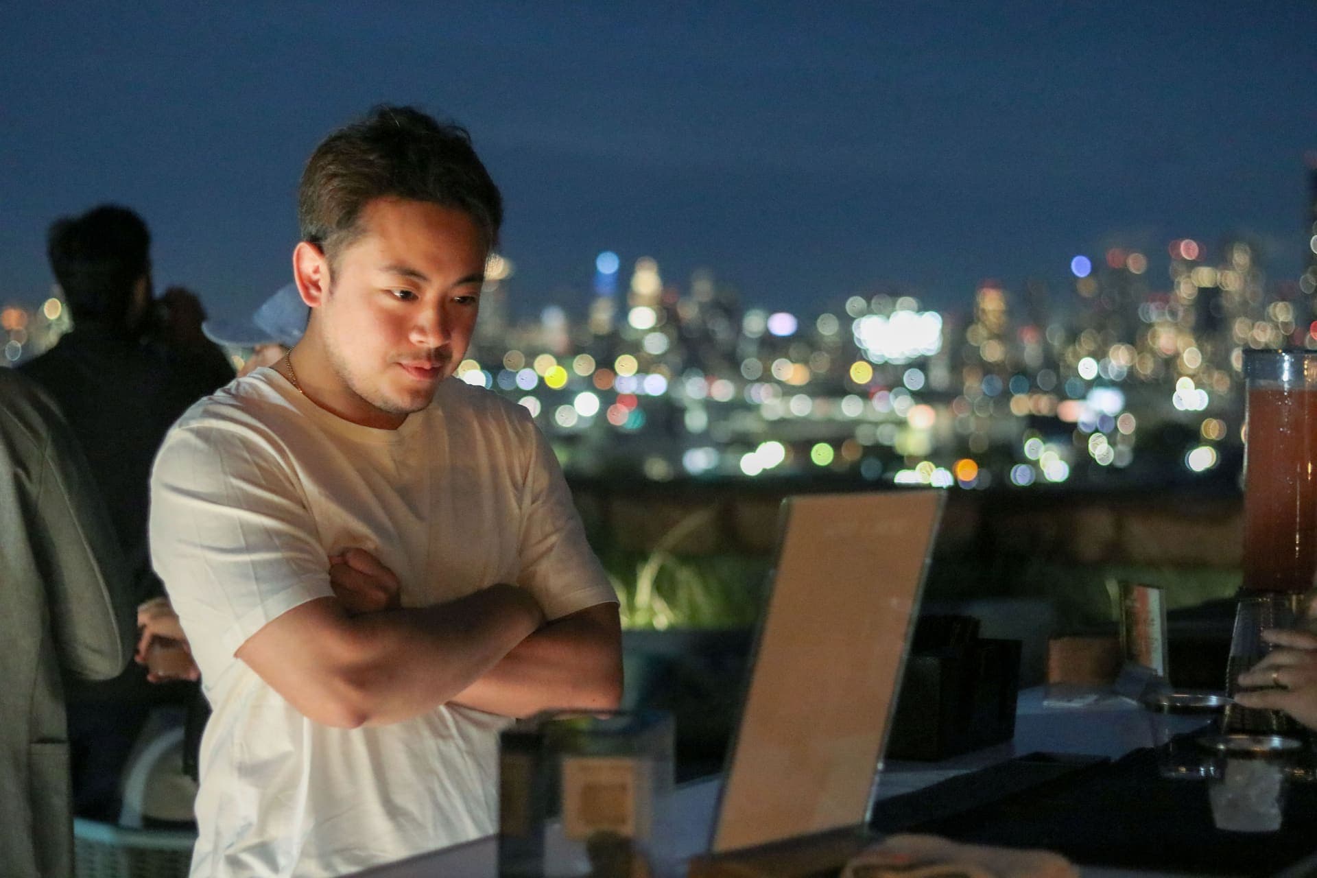 A resident at the rooftop bar at night with the lights of the city scattered behind at 875 Fourth Avenue