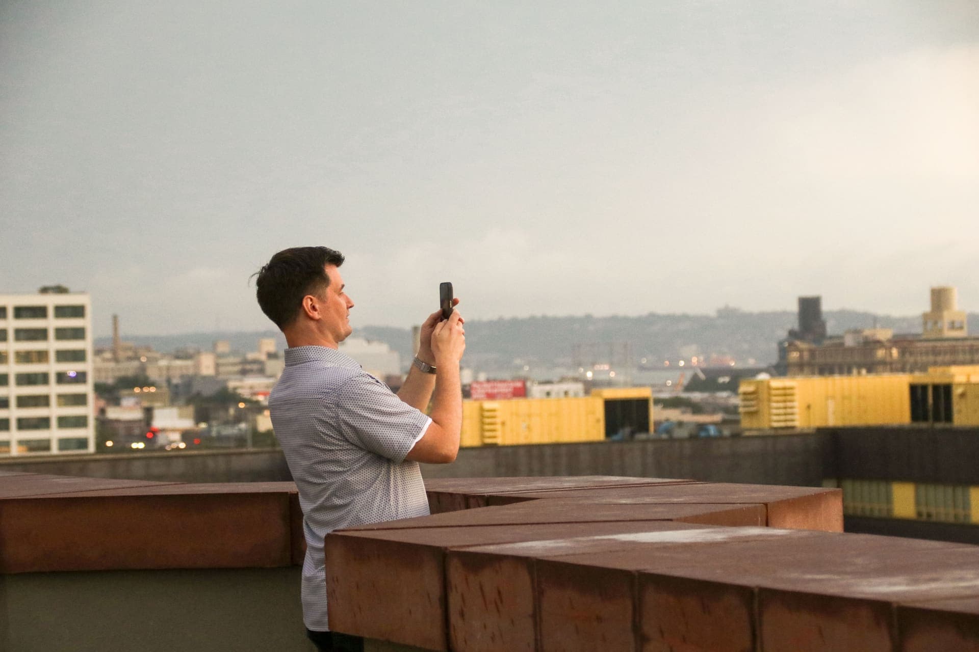 A resident raising a phone to photograph the view from the rooftop terrace at 875 Fourth Avenue