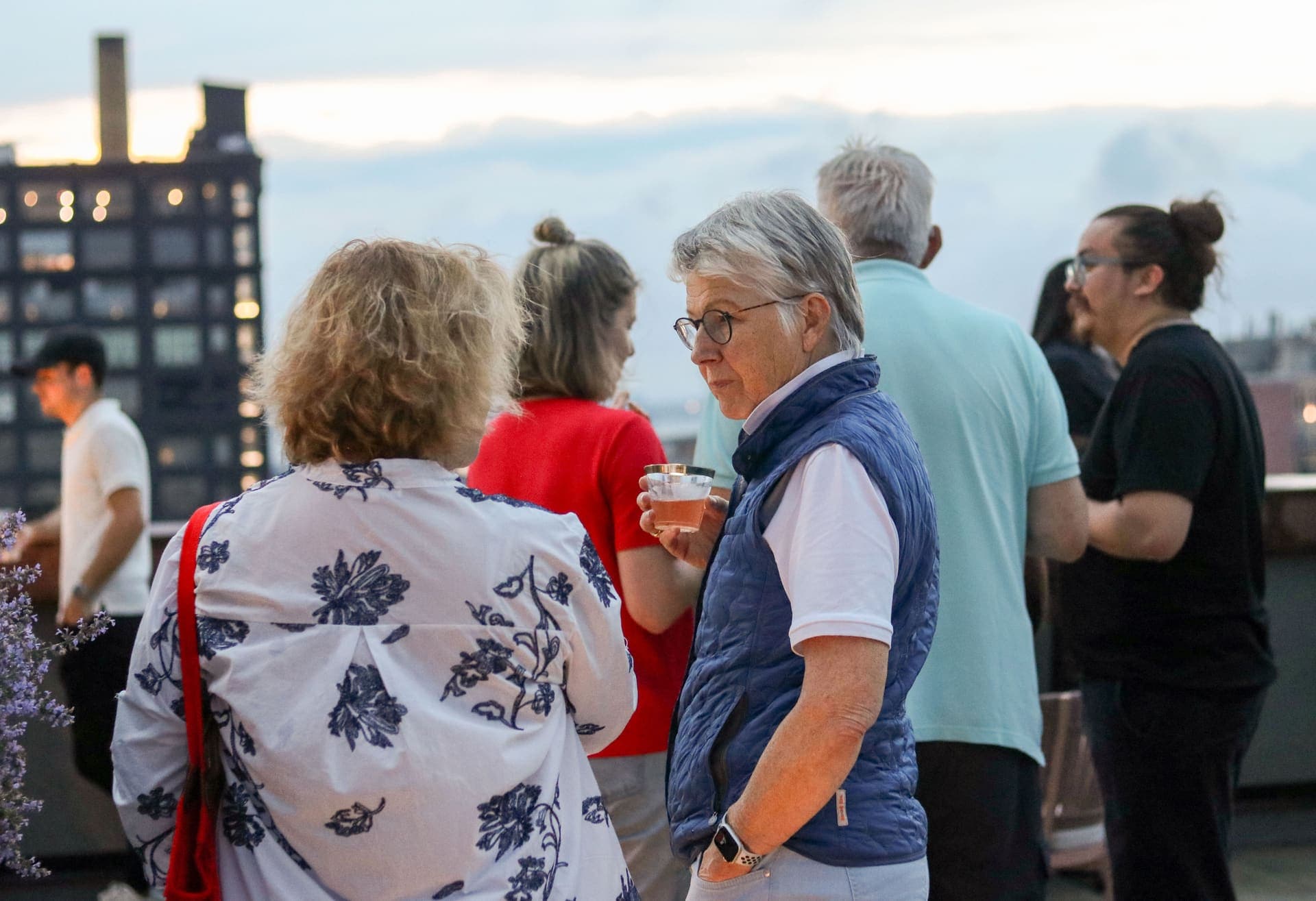 Residents talking on the terrace as the windows of nearby buildings begin to glow at 875 Fourth Avenue