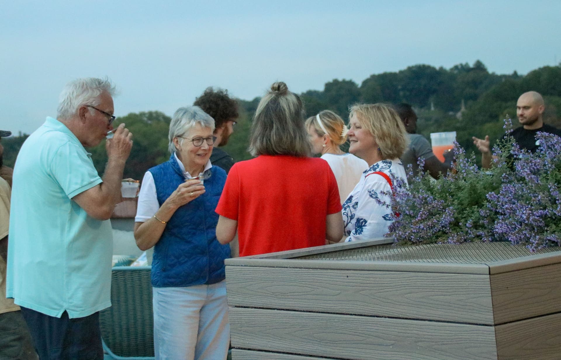 Residents in conversation beside the flowering terrace planters at dusk at 875 Fourth Avenue