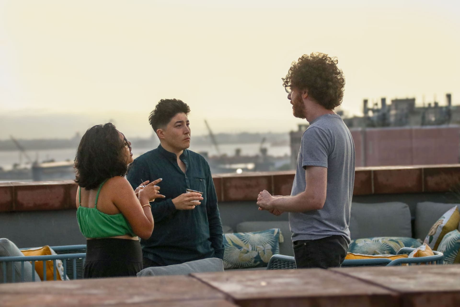 Three residents talking together on the rooftop terrace in warm evening light at 875 Fourth Avenue