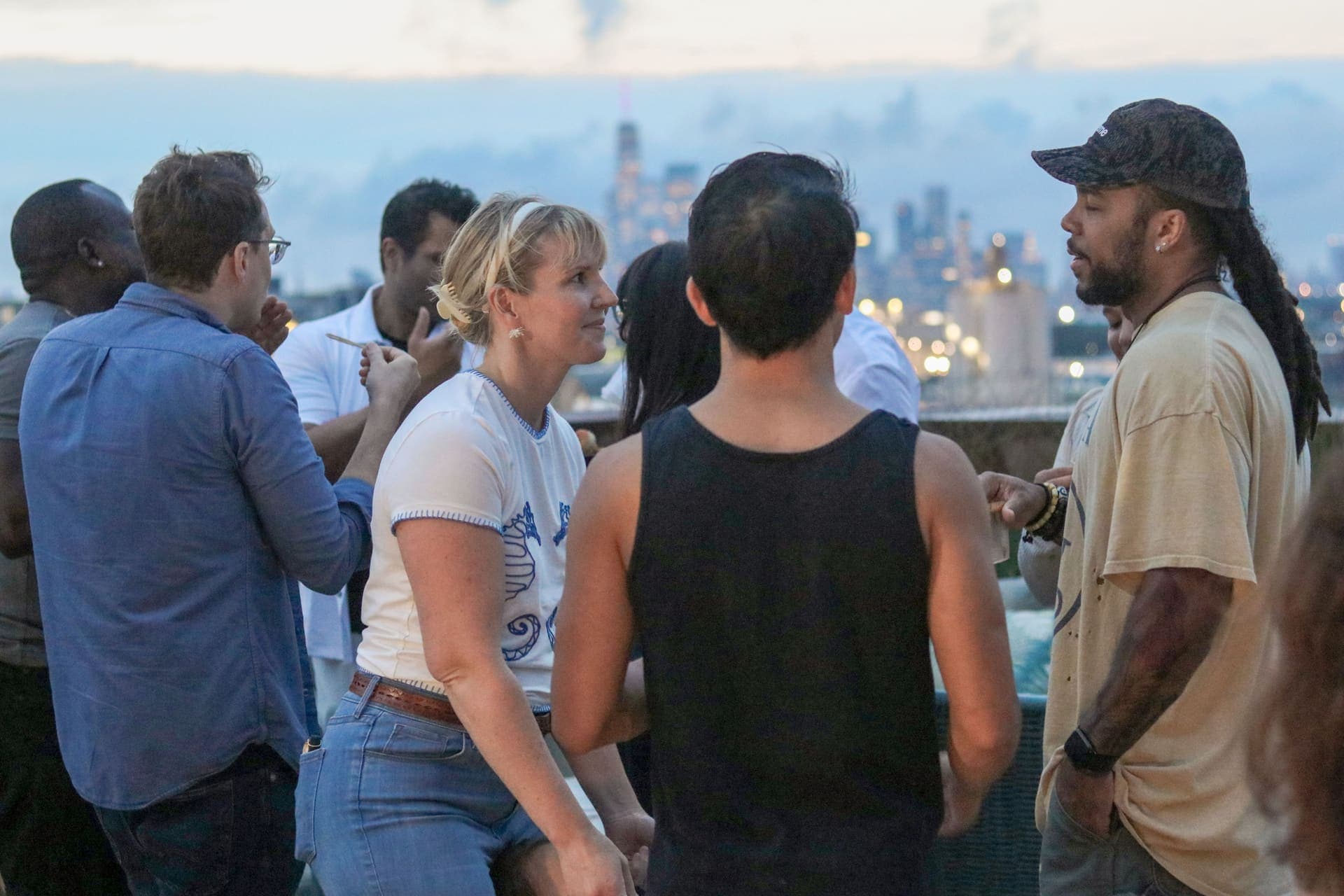 A group of residents mingling on the rooftop terrace with the downtown skyline beyond at 875 Fourth Avenue
