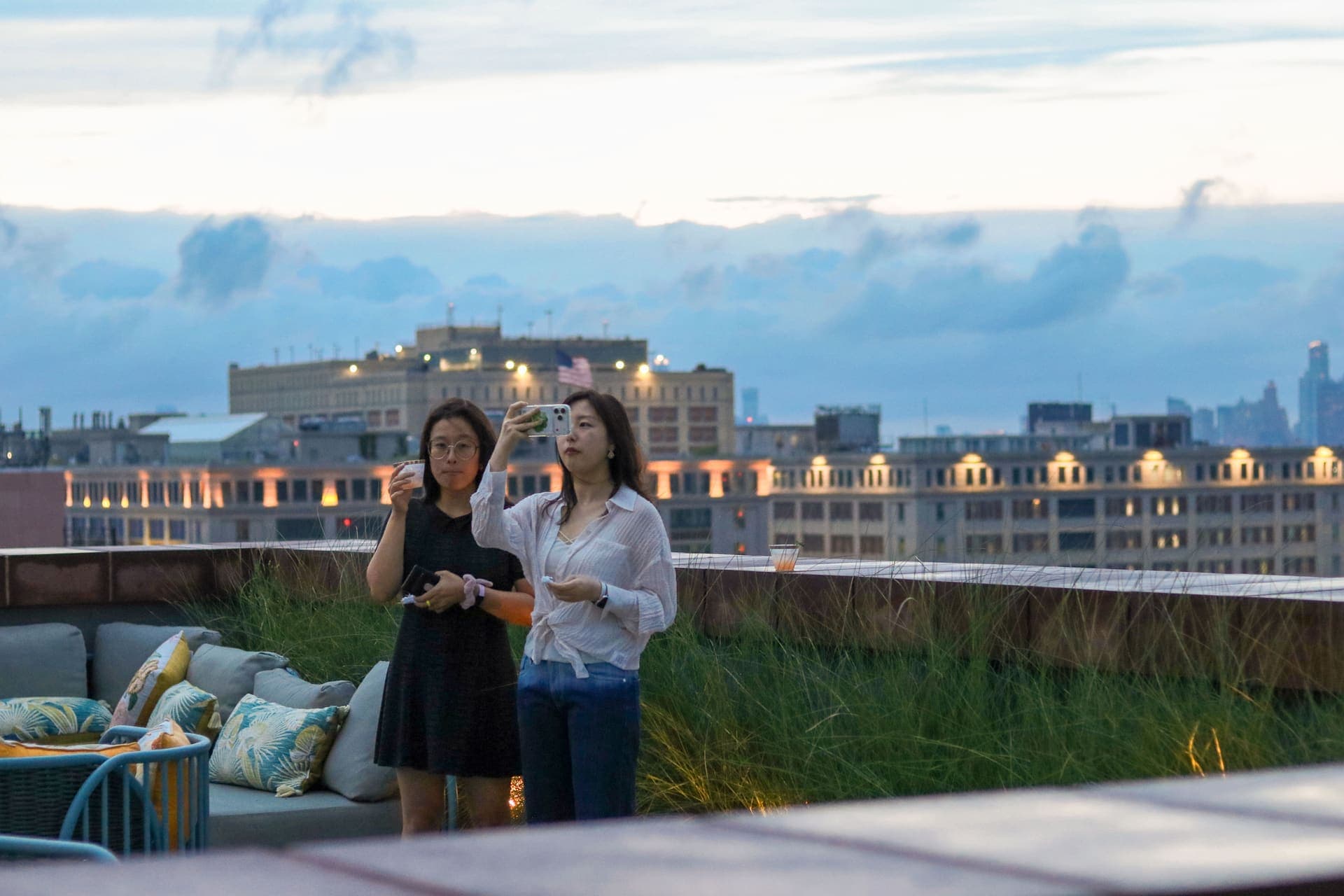 A resident photographing the lit skyline from the rooftop terrace at 875 Fourth Avenue
