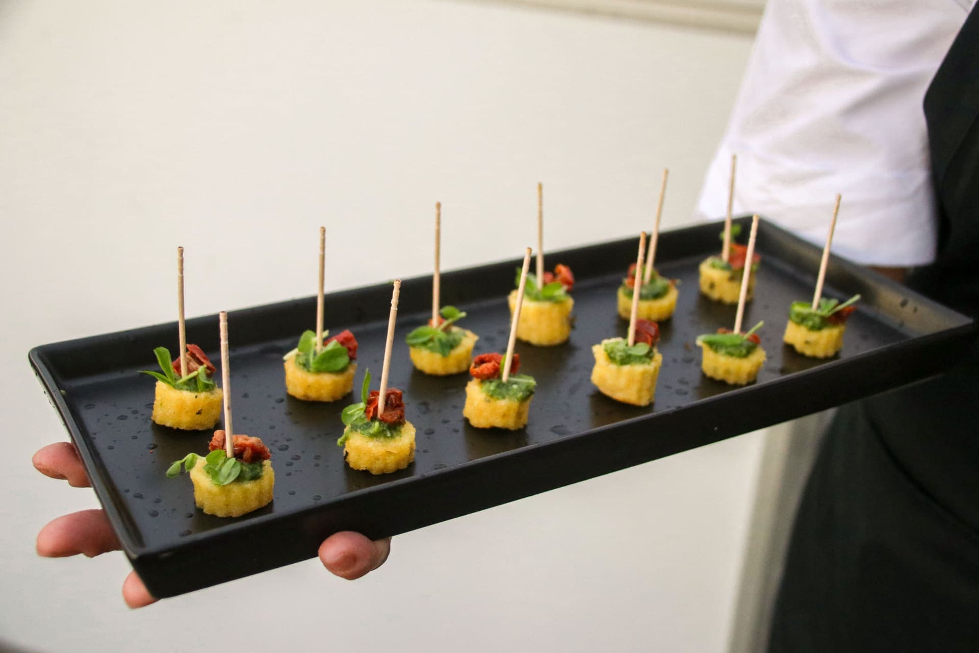 Skewered polenta bites arranged on a slate tray at the Dusk and Tonic rooftop gathering at 875 Fourth Avenue