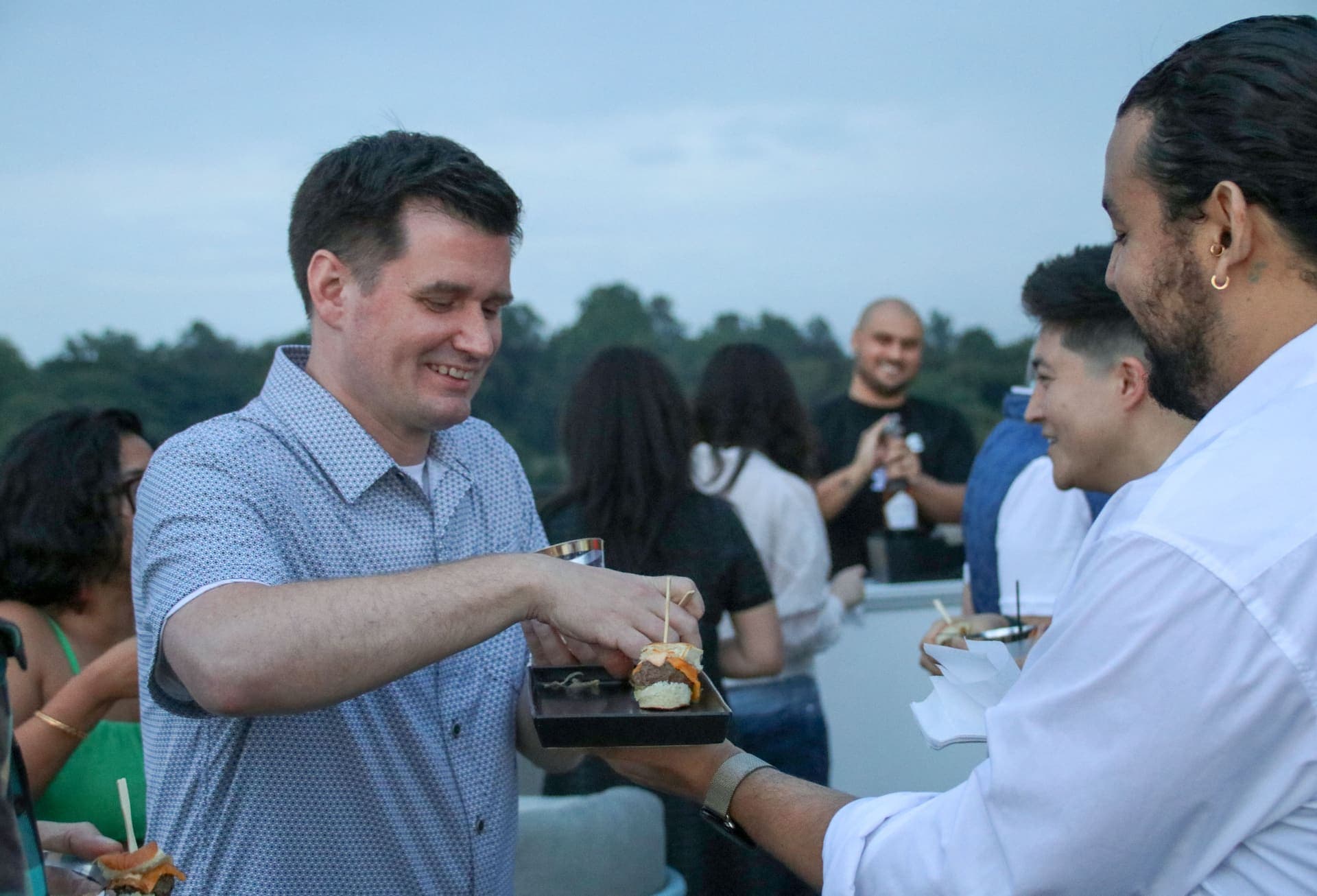 A guest taking a slider from a passed tray on the rooftop terrace at 875 Fourth Avenue