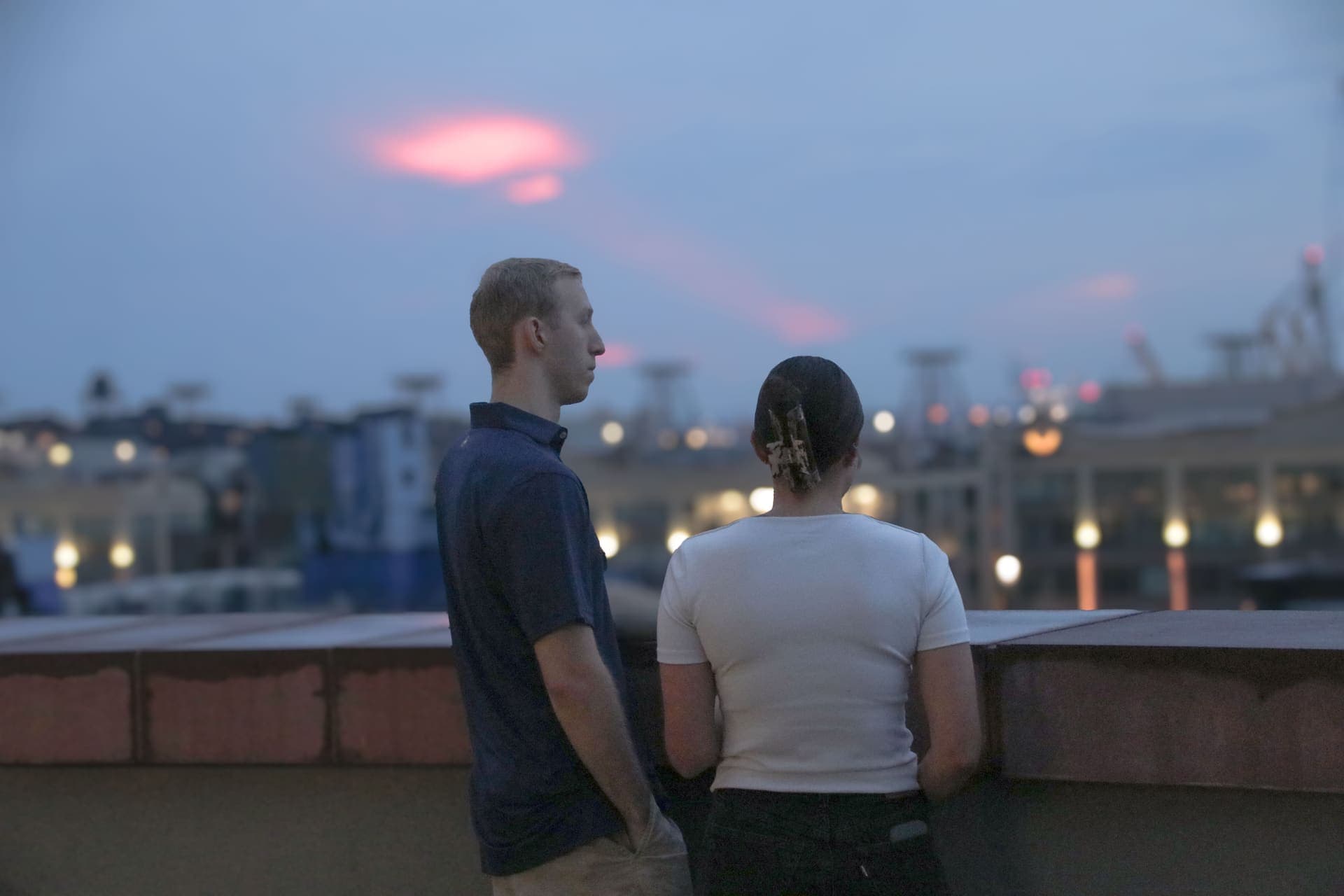 Two residents at the terrace parapet beneath a band of pink cloud at dusk at 875 Fourth Avenue
