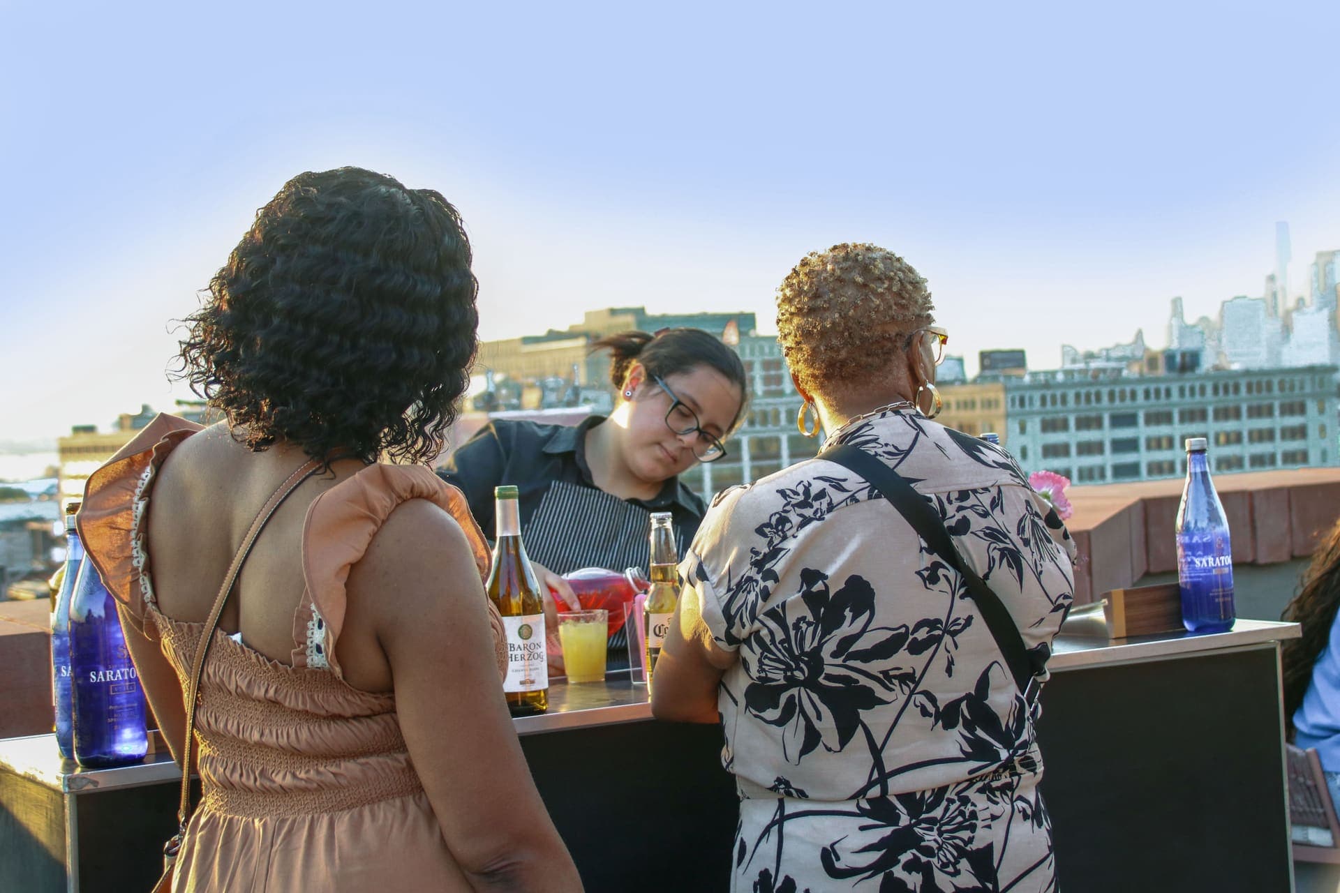 The bartender pouring at the counter as guests look on, on the rooftop terrace at 875 Fourth Avenue