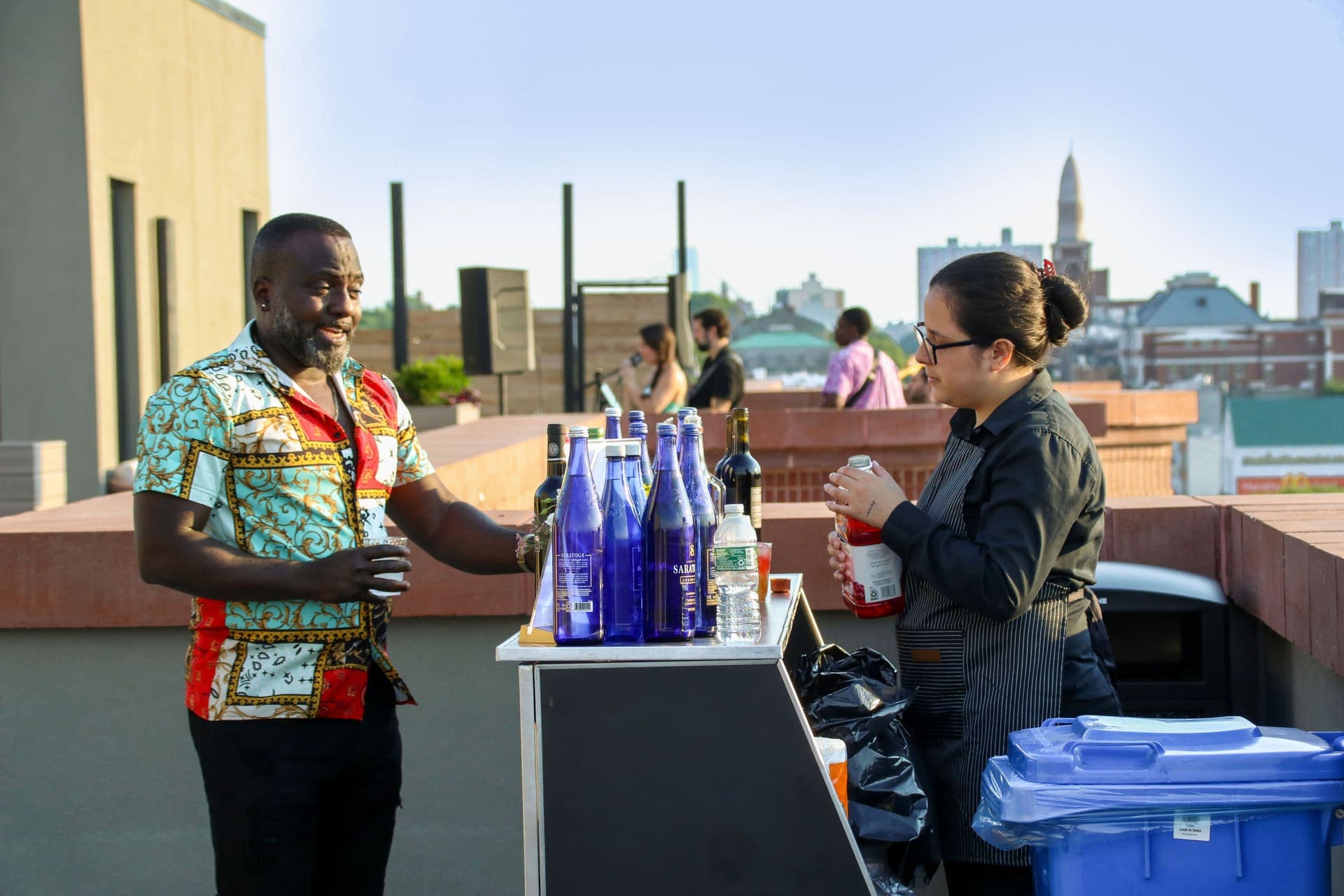 Guests at the drink cart with the band playing behind them on the rooftop terrace at 875 Fourth Avenue