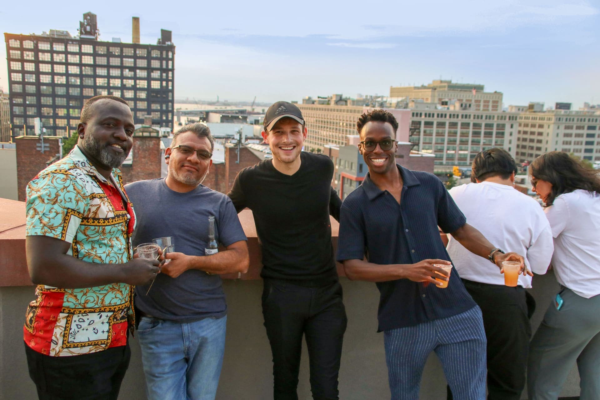 A group of friends posing together with the skyline behind them on the rooftop at 875 Fourth Avenue