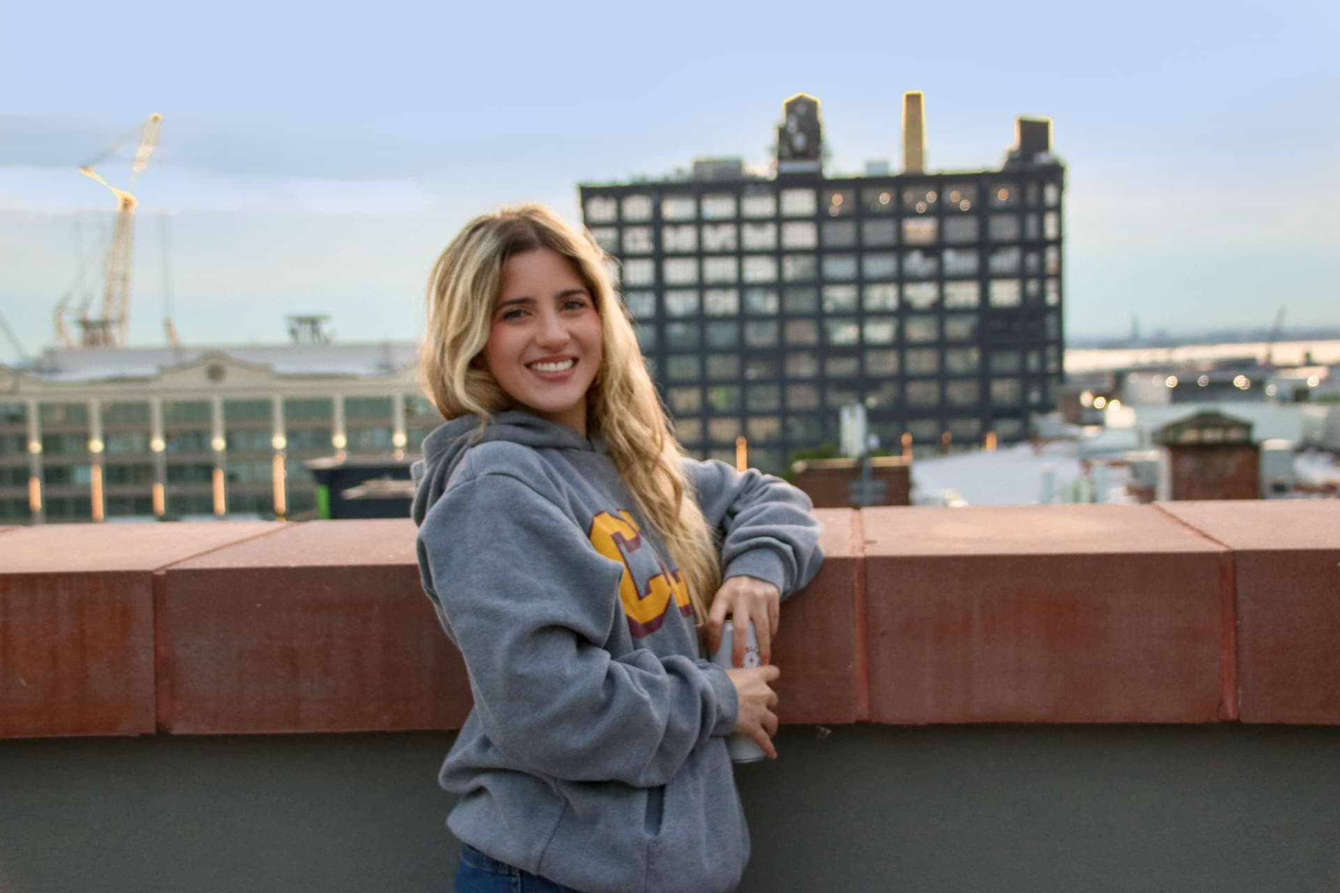 A resident photographed with the Brooklyn skyline behind on the rooftop terrace at 875 Fourth Avenue