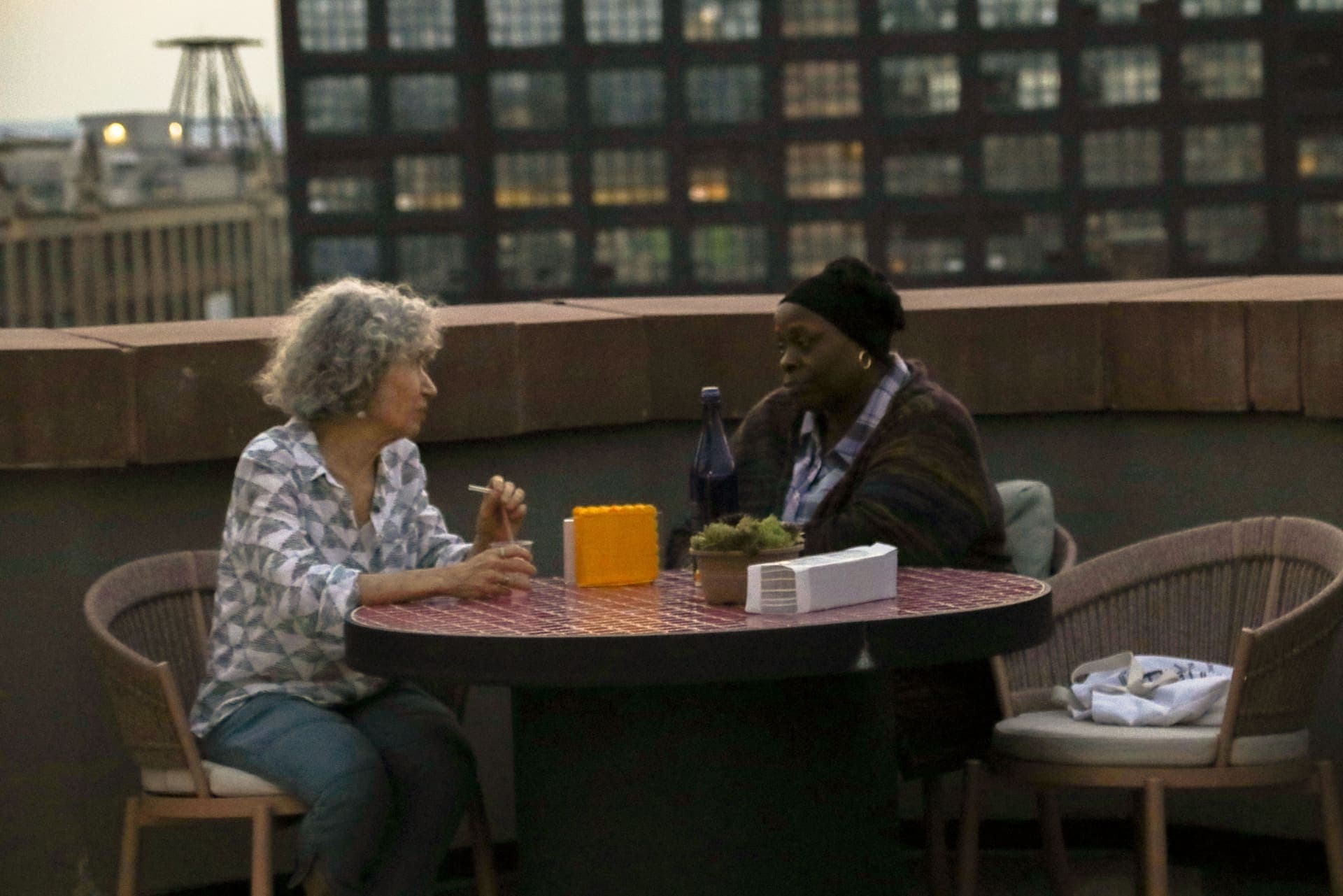 Two neighbors talking at a terrace table on the rooftop at 875 Fourth Avenue