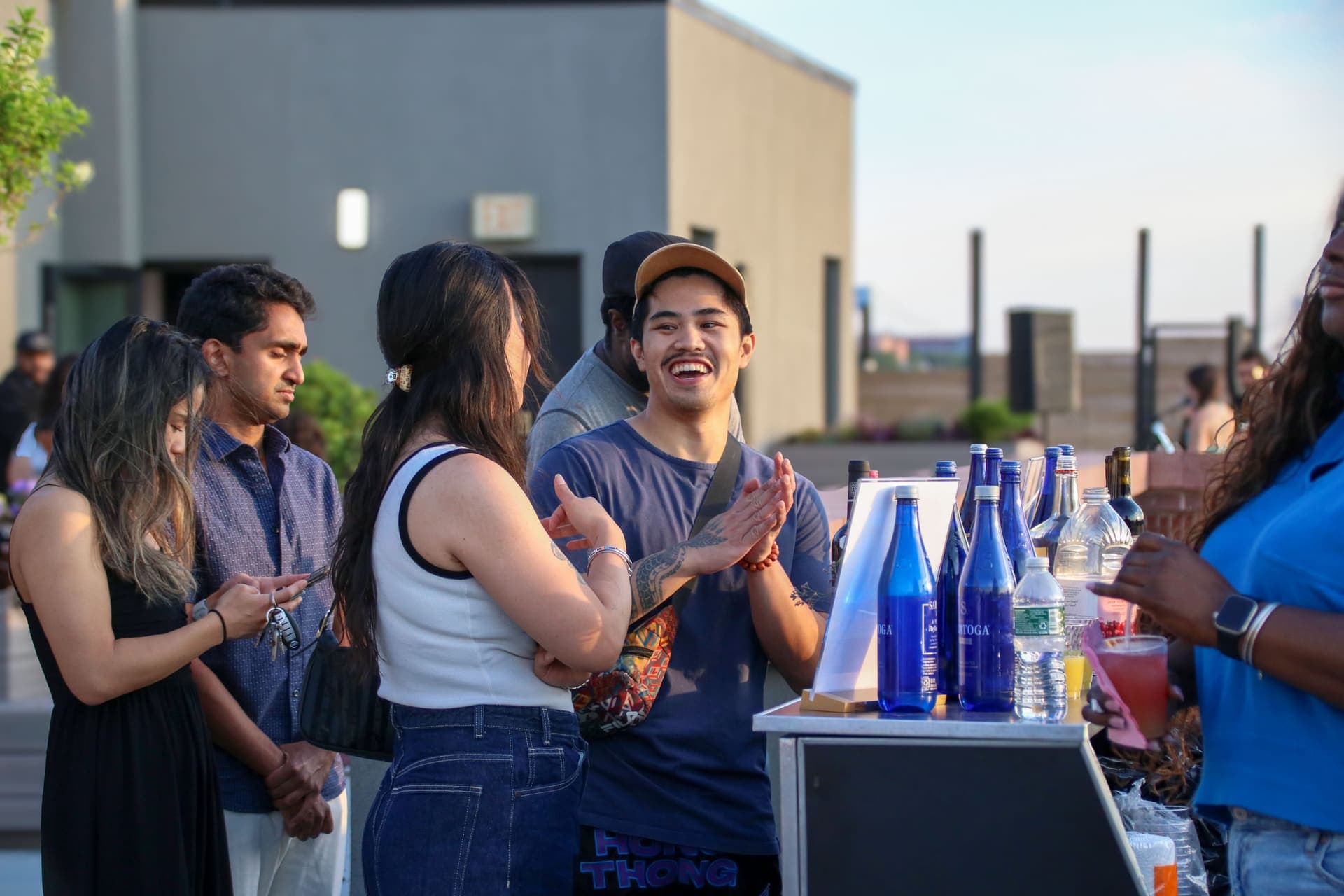 Residents laughing and clapping together at the bar on the rooftop terrace at 875 Fourth Avenue