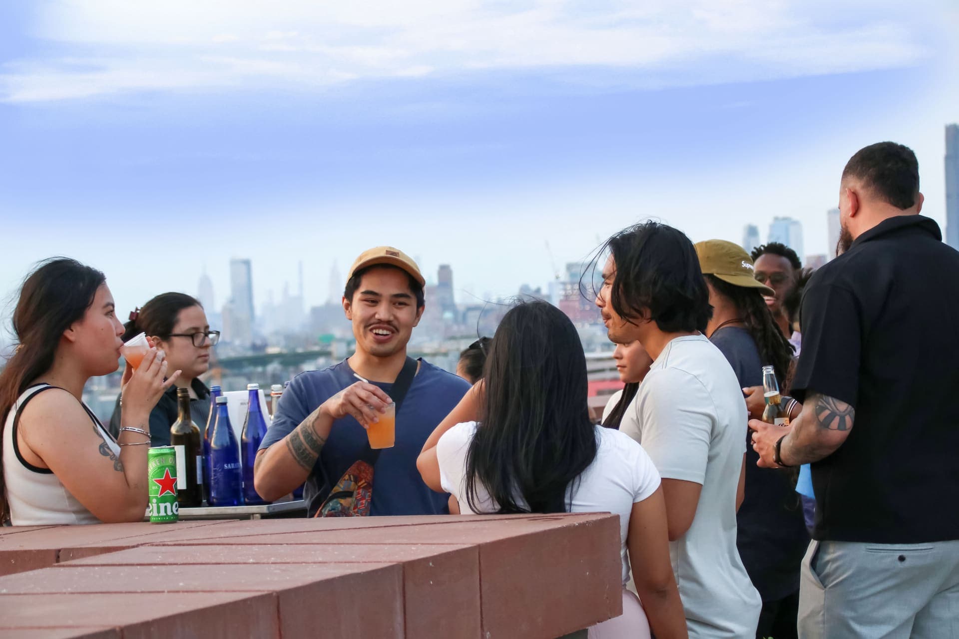 Residents catching up over drinks with the skyline behind on the rooftop at 875 Fourth Avenue
