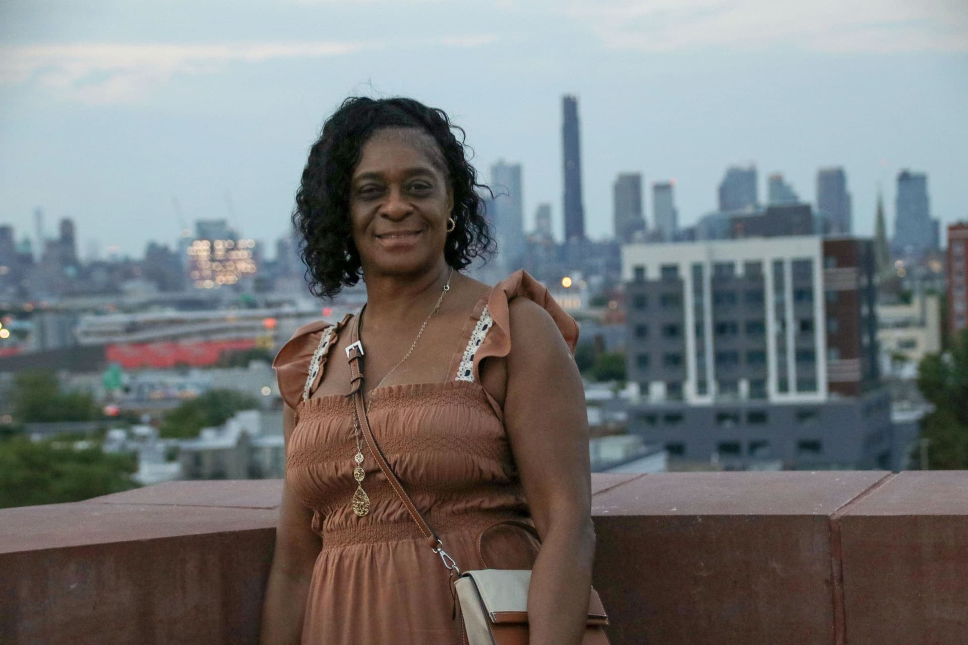 A resident photographed at dusk with the skyline behind on the rooftop terrace at 875 Fourth Avenue