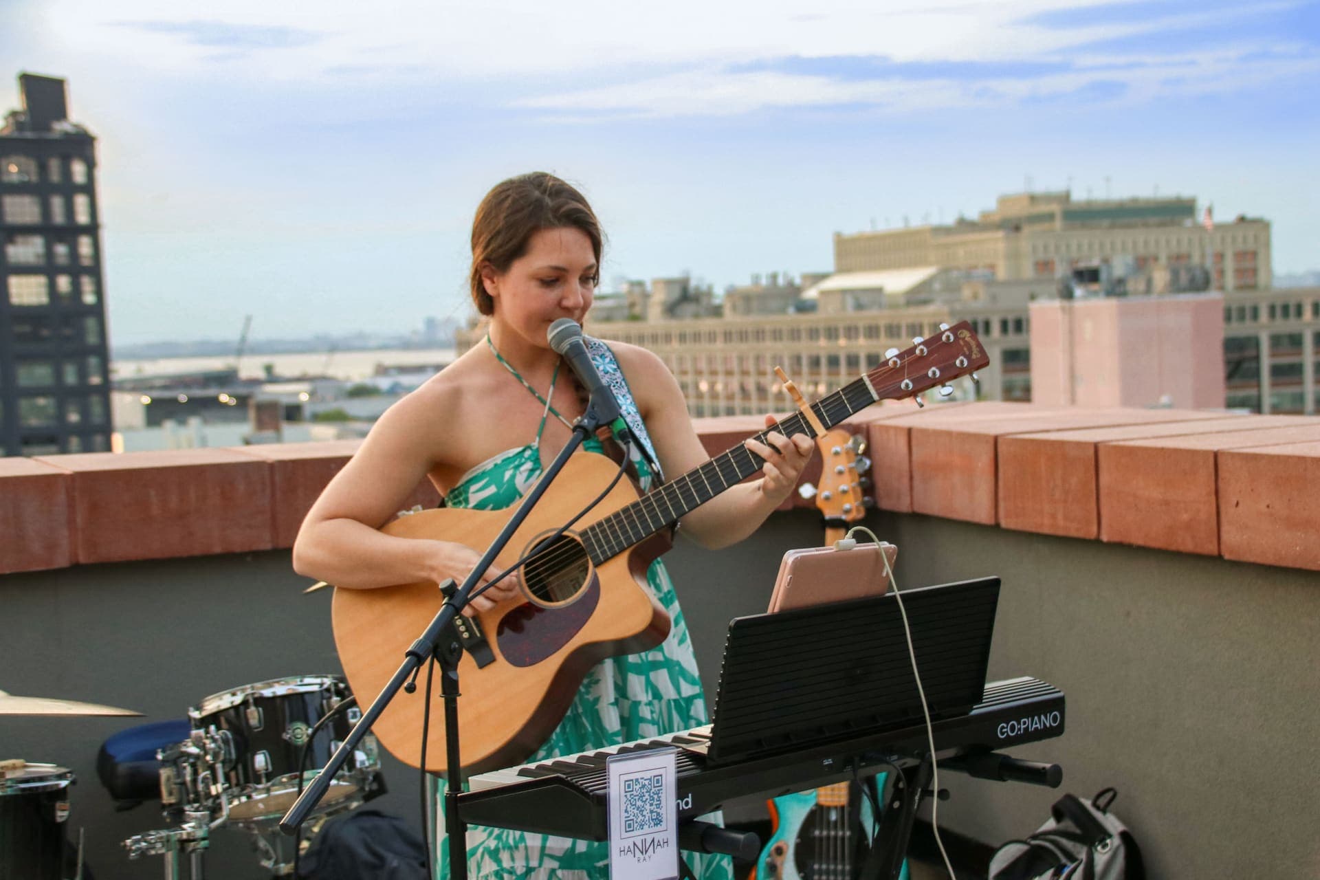 A solo singer performing with an acoustic guitar at golden hour on the rooftop terrace at 875 Fourth Avenue